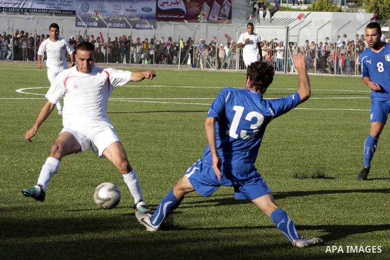 A Palestinian player is challenged by Italy player during a friendly football match between the Palestinian and Italian Olympic teams to mark the inauguration of the Dura Stadium near the West Bank city of Hebron on June...