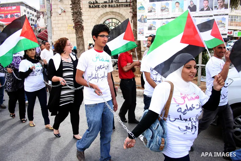 Palestinians hold national flags and banners calling for the release of prisoners for political reasons by the Palestinian security forces during a protest in the West Bank city of Ramallah, on June 13,2011. Photo by Iss...