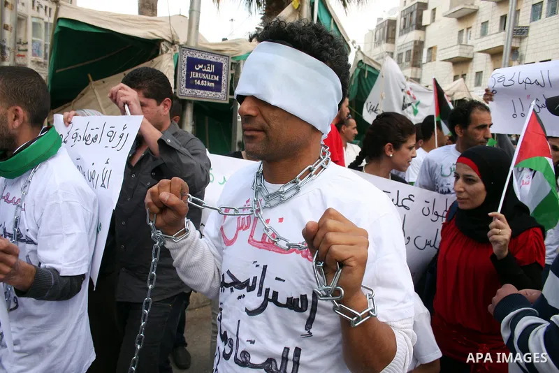 Palestinians hold national flags and banners calling for the release of prisoners for political reasons by the Palestinian security forces during a protest in the West Bank city of Ramallah, on June 13,2011. Photo by Iss...
