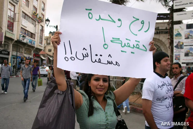 A Palestinian woman holds a banner calling for the release of prisoners for political reasons by the Palestinian security forces during a protest in the West Bank city of Ramallah, on June 13,2011. Photo by Issam Rimawi