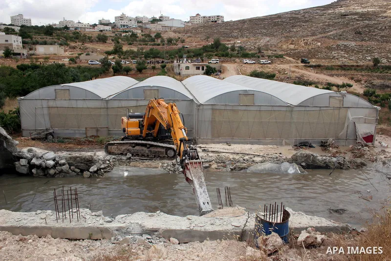 Israeli army machinery destroy a water reservoir used by Palestinian farmers in Hebron, in the Israeli-occupied West Bank, on June 14,2011. Photo by Najeh Hahlamoun.