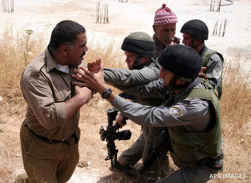 Palestinians argue with Israeli border guards as Israeli army machinery destroy a water reservoir used by Palestinian farmers in Hebron, in the Israeli-occupied West Bank, on June 14,2011. Photo by Najeh Hahlamoun.