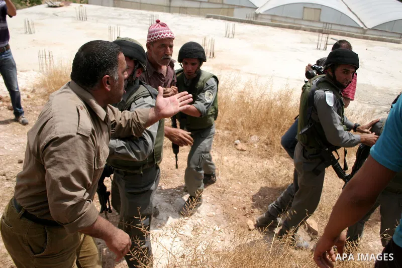 Palestinians argue with Israeli border guards as Israeli army machinery destroy a water reservoir used by Palestinian farmers in Hebron, in the Israeli-occupied West Bank, on June 14,2011. Photo by Najeh Hahlamoun.