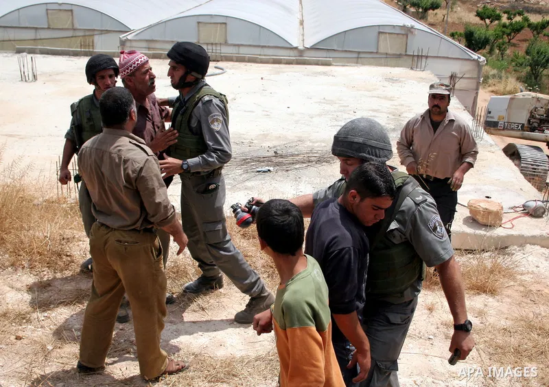 Palestinians argue with Israeli border guards as Israeli army machinery destroy a water reservoir used by Palestinian farmers in Hebron, in the Israeli-occupied West Bank, on June 14,2011. Photo by Najeh Hahlamoun.