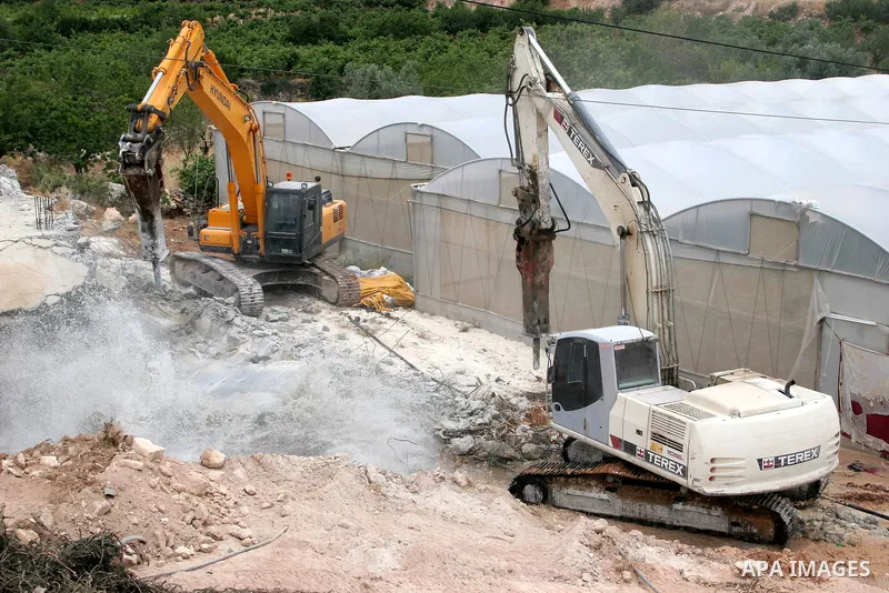Israeli army machinery destroy a water reservoir used by Palestinian farmers in Hebron, in the Israeli-occupied West Bank, on June 14,2011. Photo by Najeh Hahlamoun.