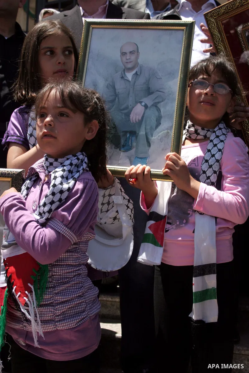Palestinians hold pictures of their jailed relatives during a protest calling for the release of prisoners from Israeli jails, outside the Red Cross offices in the West Bank city of Hebron on June 15, 2011. Photo by Naje...