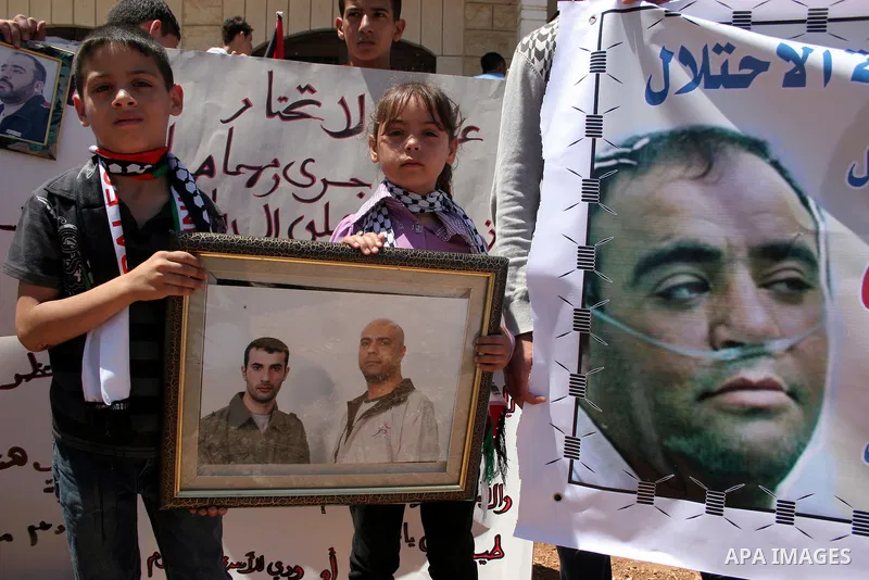 Palestinians hold pictures and banners of their jailed relatives during a protest calling for the release of prisoners from Israeli jails, outside the Red Cross offices in the West Bank city of Hebron on June 15, 2011. P...