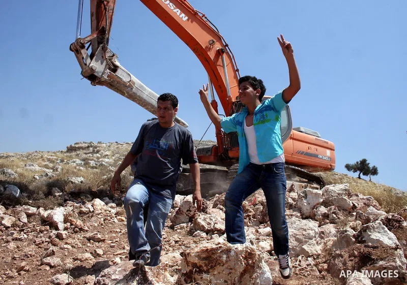 Palestinians from the village of Deir Qadis near Ramallah try to prevent Israeli bulldozers from progressing towards their land during a demonstration against the expansion of nearby settlements on June 15, 2011, in the...
