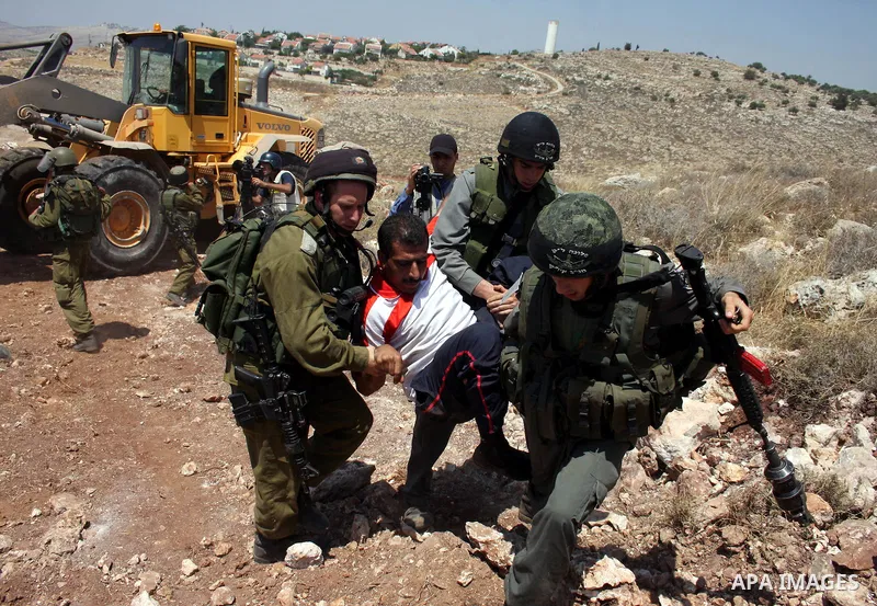 Israeli soldiers arrest a Palestinian protestor as residents from the village of Deir Qadis near Ramallah tried to prevent Israeli bulldozers from progressing towards their land during a demonstration against the expansi...