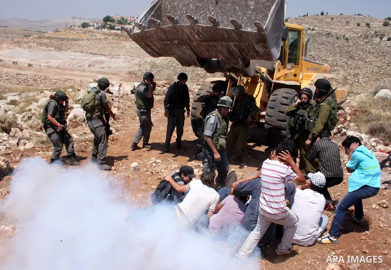 Palestinians from the village of Deir Qadis near Ramallah try to prevent Israeli bulldozers from progressing towards their land during a demonstration against the expansion of nearby settlements on June 15, 2011, in the...
