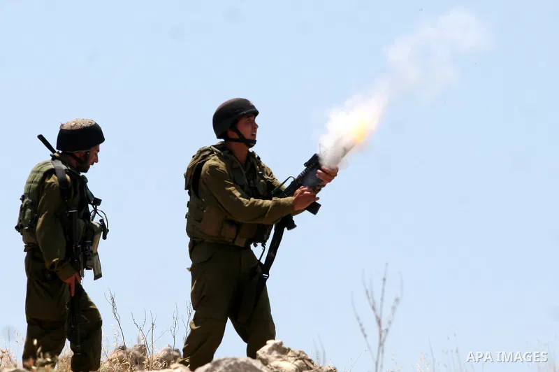 An Israeli soldier fires tear gas canister toward Palestinian protestors as residents from the village of Deir Qadis near Ramallah tried to prevent Israeli bulldozers from progressing towards their land during a demonstr...