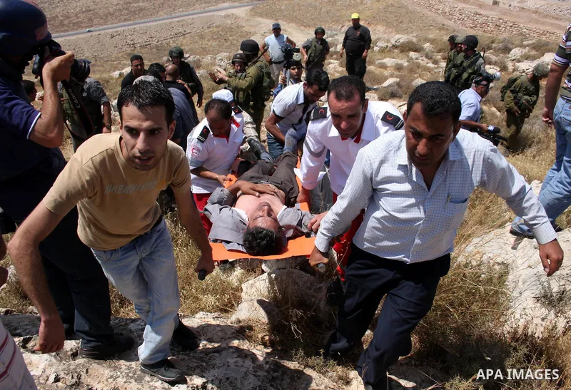 Palestinian medics carry a wounded youth as residents from the village of Deir Qadis near Ramallah tried to prevent Israeli bulldozers from progressing towards their land during a demonstration against the expansion of n...