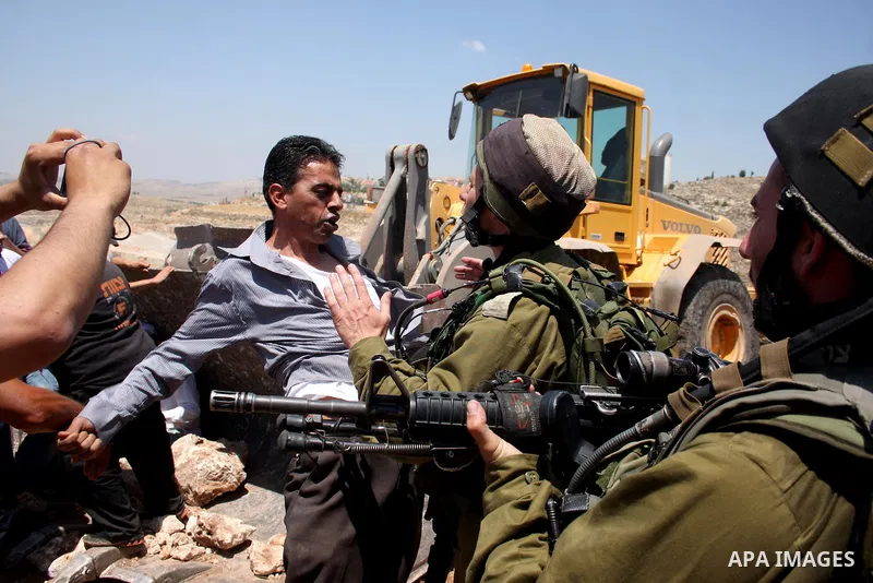 Israeli soldiers arrest a Palestinian protestor as residents from the village of Deir Qadis near Ramallah tried to prevent Israeli bulldozers from progressing towards their land during a demonstration against the expansi...
