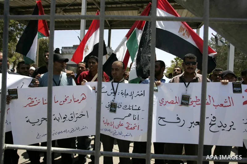 Palestinians hold their national flags and the Egyptian flags and banners during a rally in front of the Rafah border crossing in the southern Gaza Strip on June 16, 2011, demanding it to be open permanently and without...