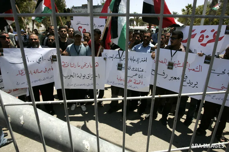 Palestinians hold their national flags and the Egyptian flags and banners during a rally in front of the Rafah border crossing in the southern Gaza Strip on June 16, 2011, demanding it to be open permanently and without...