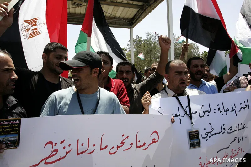 Palestinians hold their national flags and the Egyptian flags and banners during a rally in front of the Rafah border crossing in the southern Gaza Strip on June 16, 2011, demanding it to be open permanently and without...