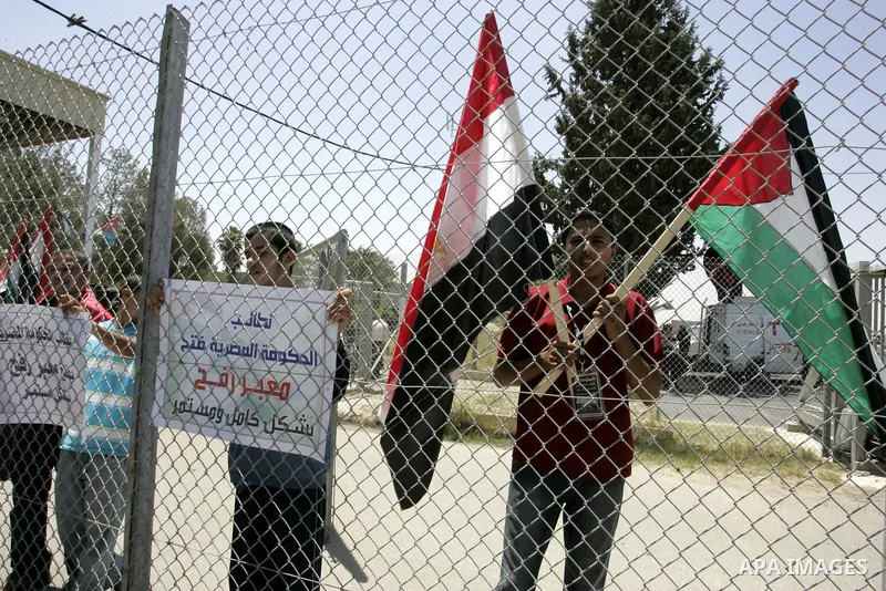 Palestinians hold their national flags and the Egyptian flags and banners during a rally in front of the Rafah border crossing in the southern Gaza Strip on June 16, 2011, demanding it to be open permanently and without...