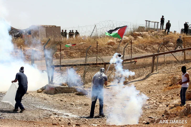 Protestors run amidst tear gas smoke fired by Israeli forces during clashes following a weekly demonstration against Israel's separation barrier in the Palestinian West Bank village of Bilin on June 17, 2011. Photo by Is...