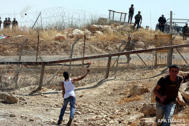 Protestors hurl stones toward Israeli forces during clashes following a weekly demonstration against Israel's separation barrier in the Palestinian West Bank village of Bilin on June 17, 2011. Photo by Issam Rimawi