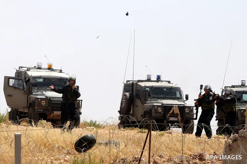 Israeli soldiers fire tear gas canisters toward protestors during clashes following a weekly demonstration against Israel's separation barrier in the Palestinian West Bank village of Bilin on June 17, 2011. Photo by Issa...