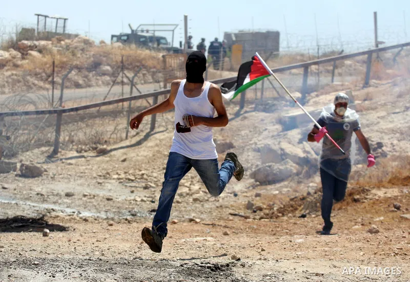 Protestors run amidst tear gas smoke fired by Israeli forces during clashes following a weekly demonstration against Israel's separation barrier in the Palestinian West Bank village of Bilin on June 17, 2011. Photo by Is...