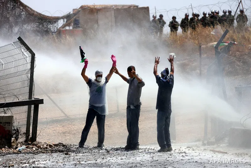 Protestors holding the Palestinian national flag face the coloured water sprayed by Israeli police water cannon vehicle during clashes following a weekly demonstration against Israel's separation barrier in the Palestini...