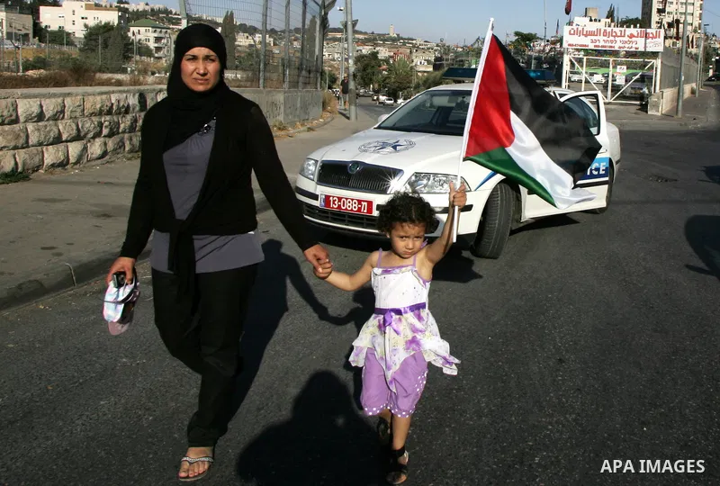 Palestinian demonstrators wave their national flag in the mostly Arab Jerusalem neighbourhood of Sheikh Jarrah on Jun 17, 2011 during a weekly demonstration by Israeli, Palestinian and international activists. Photo by M...