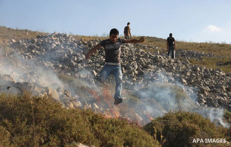 A Palestinian protester runs for cover from tear gas canister fired by Israeli soldiers during a demonstration against the expansion of Jewish settlements on June 18, 2011 in the village of Iraq Burin, south of the north...
