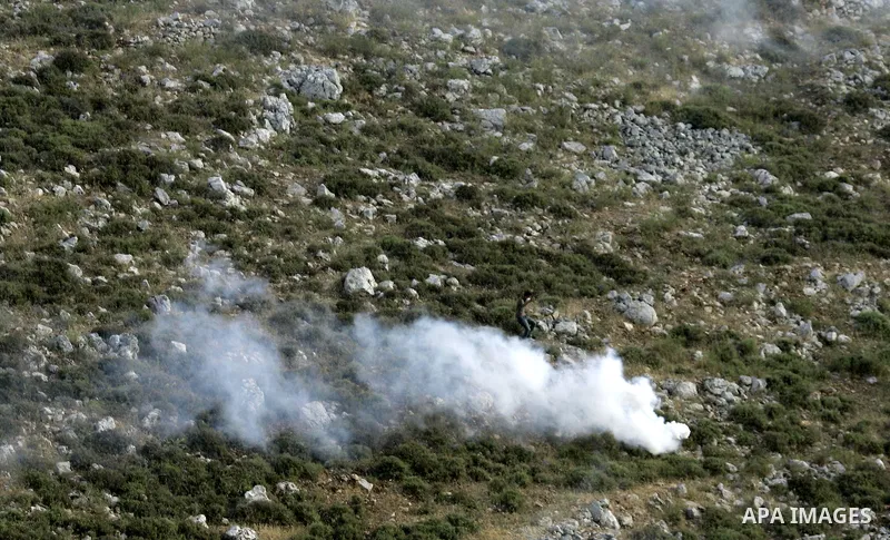 A Palestinian protester runs for cover from tear gas canister fired by Israeli soldiers during a demonstration against the expansion of Jewish settlements on June 18, 2011 in the village of Iraq Burin, south of the north...