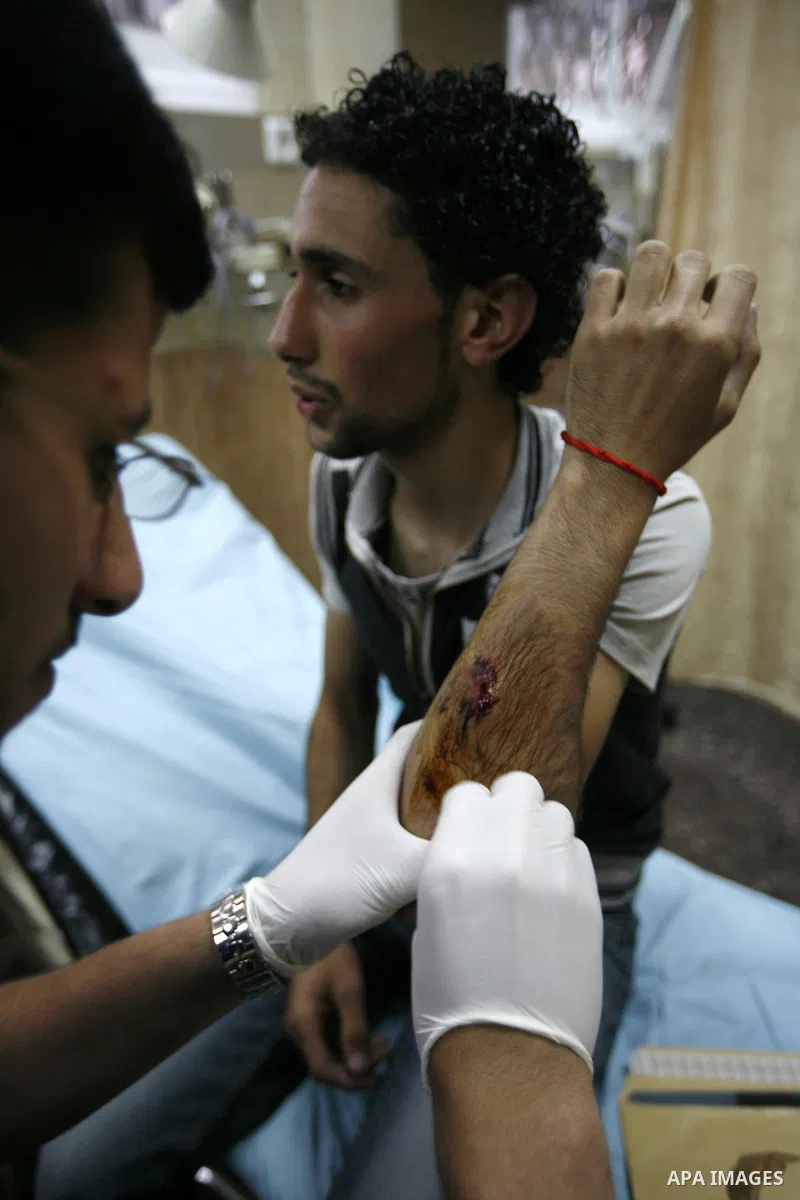 Palestinians evacuate a wounded press photographer during a demonstration against the expansion of Jewish settlements on June 18, 2011 in the village of Iraq Burin, south of the northern West Bank city Nablus. Photo by N...