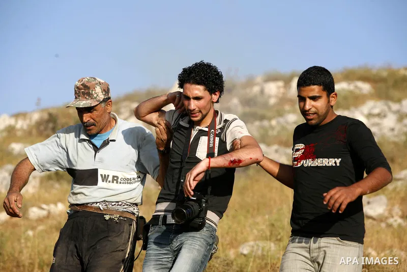 Palestinians evacuate a wounded press photographer during a demonstration against the expansion of Jewish settlements on June 18, 2011 in the village of Iraq Burin, south of the northern West Bank city Nablus. Photo by N...