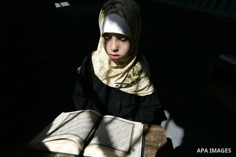 A Palestinian girl reads the Koran at a summer camp for the study of Islam's holy book organised by the Islamist movement Hamas in Rafah in the southern of Gaza Strip on June 19, 2011. Photo by Abed Rahim Khatib