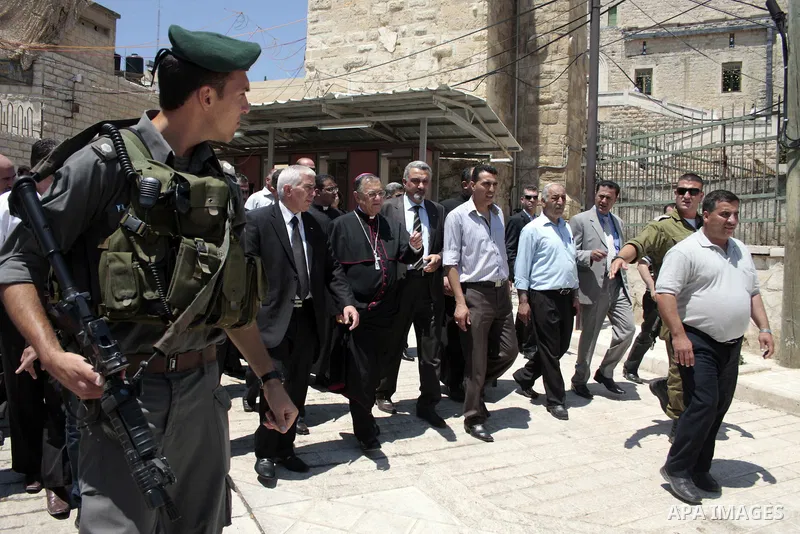 The head of the Roman Catholic Church in the Holy Land, the Latin Patriarch of Jerusalem Fuad Twal walks among Palestinian officials near the Ibrahimi Mosque, or Tomb of the Patriarchs, during a visit to the divided West...