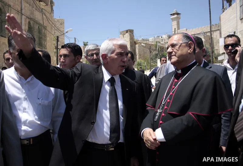 The head of the Roman Catholic Church in the Holy Land, the Latin Patriarch of Jerusalem Fuad Twal walks among Palestinian officials near the Ibrahimi Mosque, or Tomb of the Patriarchs, during a visit to the divided West...