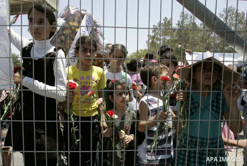 Palestinian children hold flowers during a rally in front of the Rafah border crossing with Egypt in the southern Gaza Strip on June 21, 2011, demanding it to be open permanently and without restrictions or conditions on...