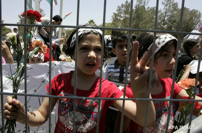 Palestinian children hold flowers during a rally in front of the Rafah border crossing with Egypt in the southern Gaza Strip on June 21, 2011, demanding it to be open permanently and without restrictions or conditions on...