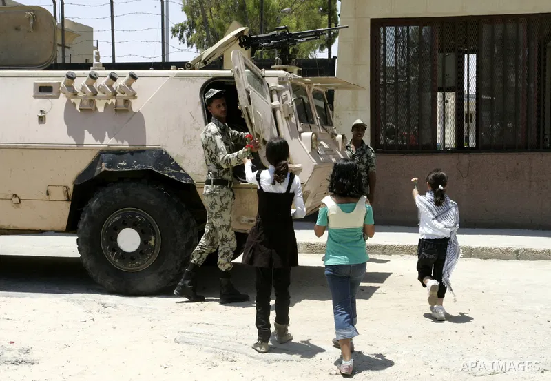 Palestinian children hand out flowers to Egyptian soldiers during a rally in front of the Rafah border crossing with Egypt in the southern Gaza Strip on June 21, 2011, demanding it to be open permanently and without rest...