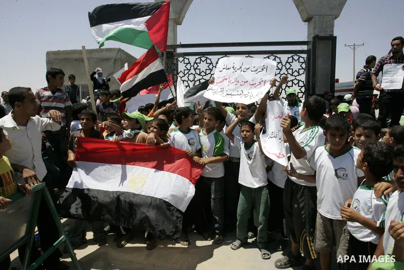 Palestinian children hold banners and Egyptian flag during a rally in front of the Rafah border crossing with Egypt in the southern Gaza Strip on June 21, 2011, demanding it to be open permanently and without restriction...