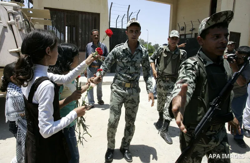 Palestinian children hand out flowers to Egyptian soldiers during a rally in front of the Rafah border crossing with Egypt in the southern Gaza Strip on June 21, 2011, demanding it to be open permanently and without rest...