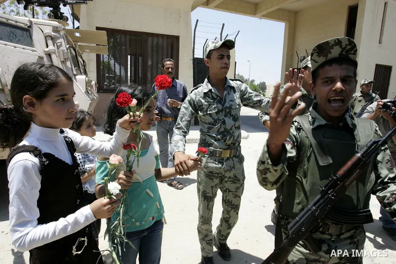 Palestinian children hand out flowers to Egyptian soldiers during a rally in front of the Rafah border crossing with Egypt in the southern Gaza Strip on June 21, 2011, demanding it to be open permanently and without rest...