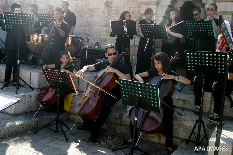 Palestinians and foreigners play the violin in front of the Damascus Gate in Jerusalem's old city on Jun 22,2011. Photo by Mahfouz Abu Turk