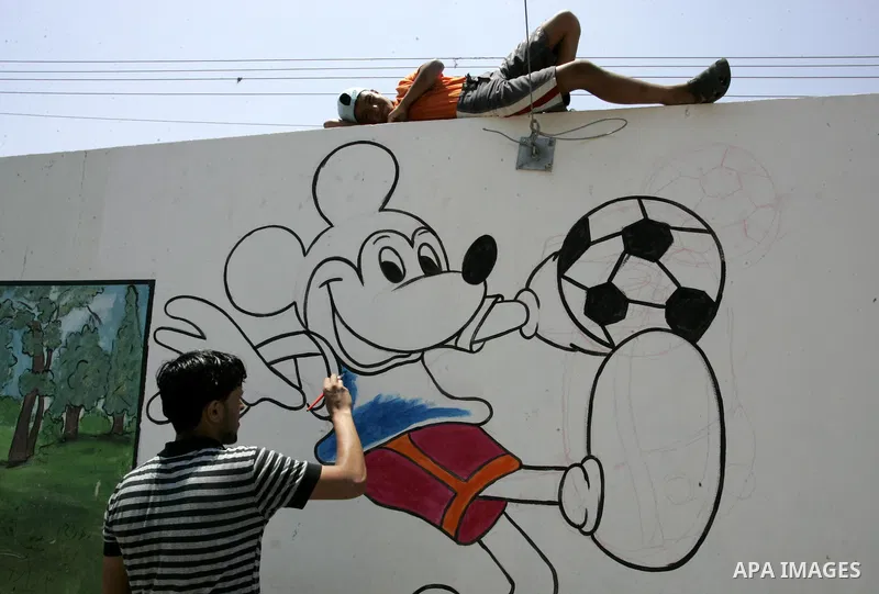 A Palestinian youth paints graffiti at a summer camp organised by UNRWA in Rafah, southern Gaza Strip on Jun 23, 2011. Photo by Abed Rahim Khatib