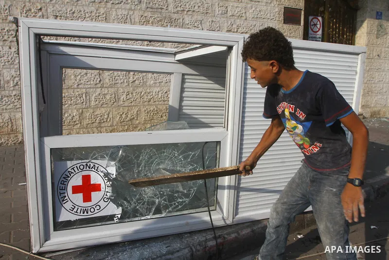 A Palestinian boy destroys the guard post outside the building housing the offices of the International Committee of the Red Cross (ICRC) as dozens of angry protesters demonstrated outside the premises of the ICRC in Gaz...