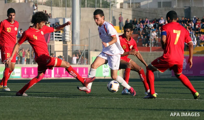 Palestinian team's player challenges the Bahrain's player during their 2012 Olympic qualifying football match in the West Bank town of Al-Ram, near Ramallah, on June 23, 2011 . Photo by Issam Rimawi
