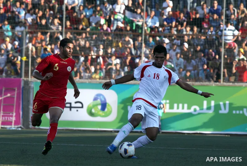 Palestinian team's player challenges the Bahrain's player during their 2012 Olympic qualifying football match in the West Bank town of Al-Ram, near Ramallah, on June 23, 2011 . Photo by Issam Rimawi