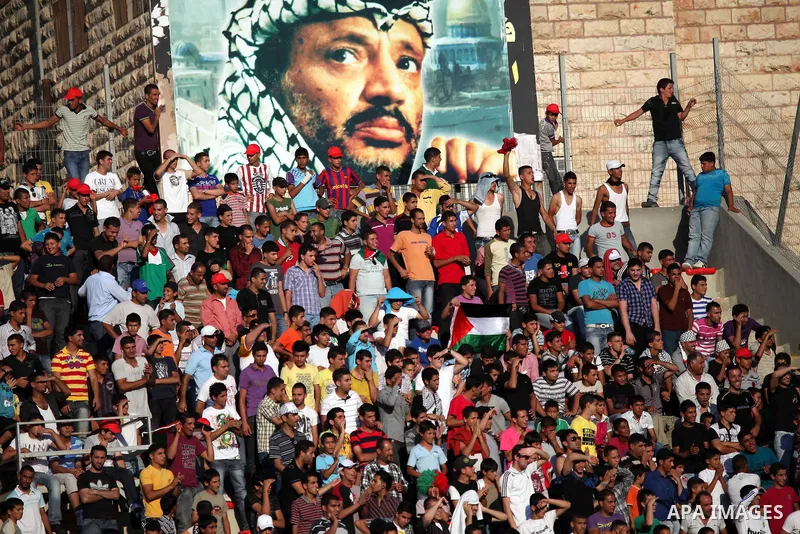 Palestinian fans attend a football match between their national team and Bahrain team during their 2012 Olympic qualifying football match in the West Bank town of Al-Ram, near Ramallah, on June 23, 2011. Photo by Issam R...