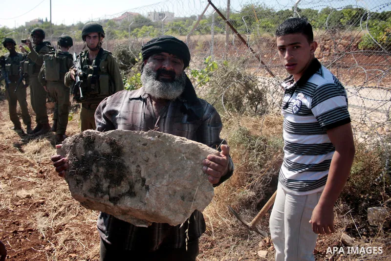 Israeli soldiers stand guards as protesters help a Palestinian farmer in his land on Jun 24, 2011 during a demonstration by foreign, Israeli and Palestinian activists against the Jewish settlement of Karmei Tzur near the...