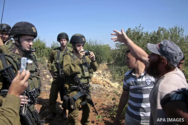 Israeli soldiers stand guards as protesters help a Palestinian farmer in his land on Jun 24, 2011 during a demonstration by foreign, Israeli and Palestinian activists against the Jewish settlement of Karmei Tzur near the...