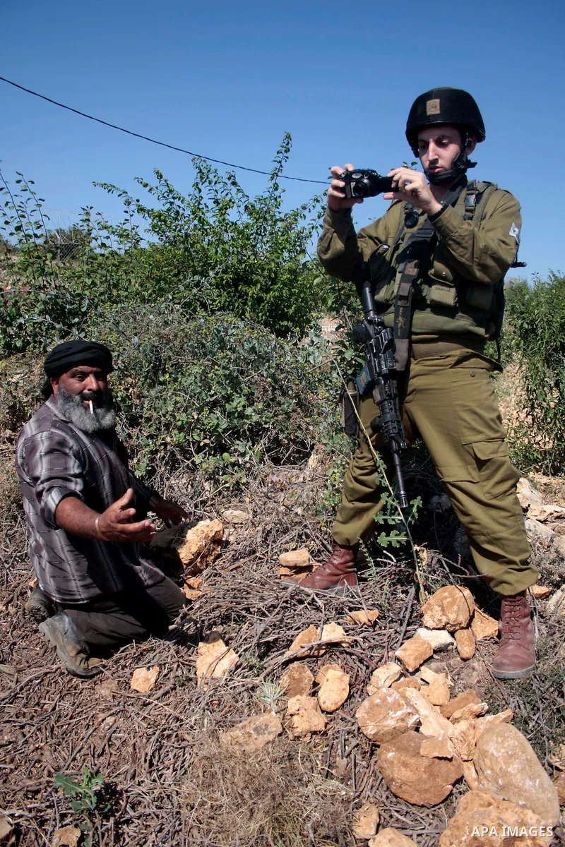Israeli soldiers stand guards as protesters help a Palestinian farmer in his land on Jun 24, 2011 during a demonstration by foreign, Israeli and Palestinian activists against the Jewish settlement of Karmei Tzur near the...