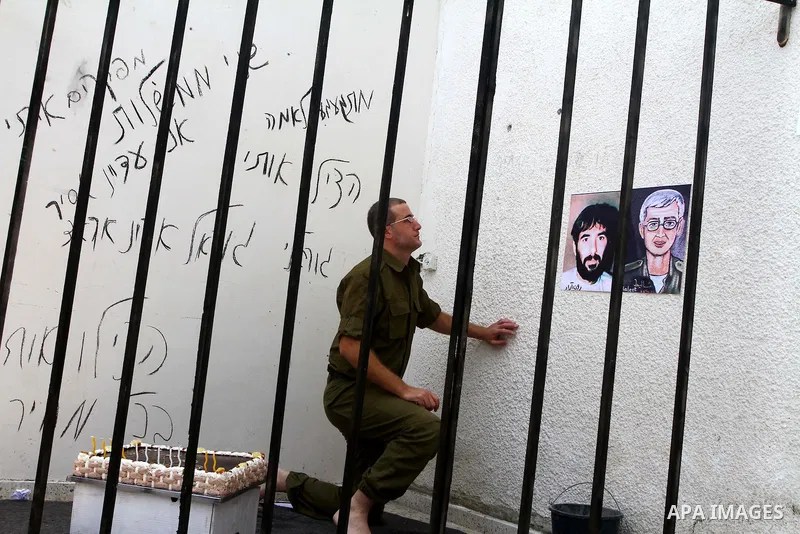 A Palestinian playing the role of Israeli soldier Gilad Shalit stands in a cage to mark the fifth anniversary of his capture by Palestinian militants, in Jabalya in the northern Gaza Strip June 25, 2011. The Hebrew writi...